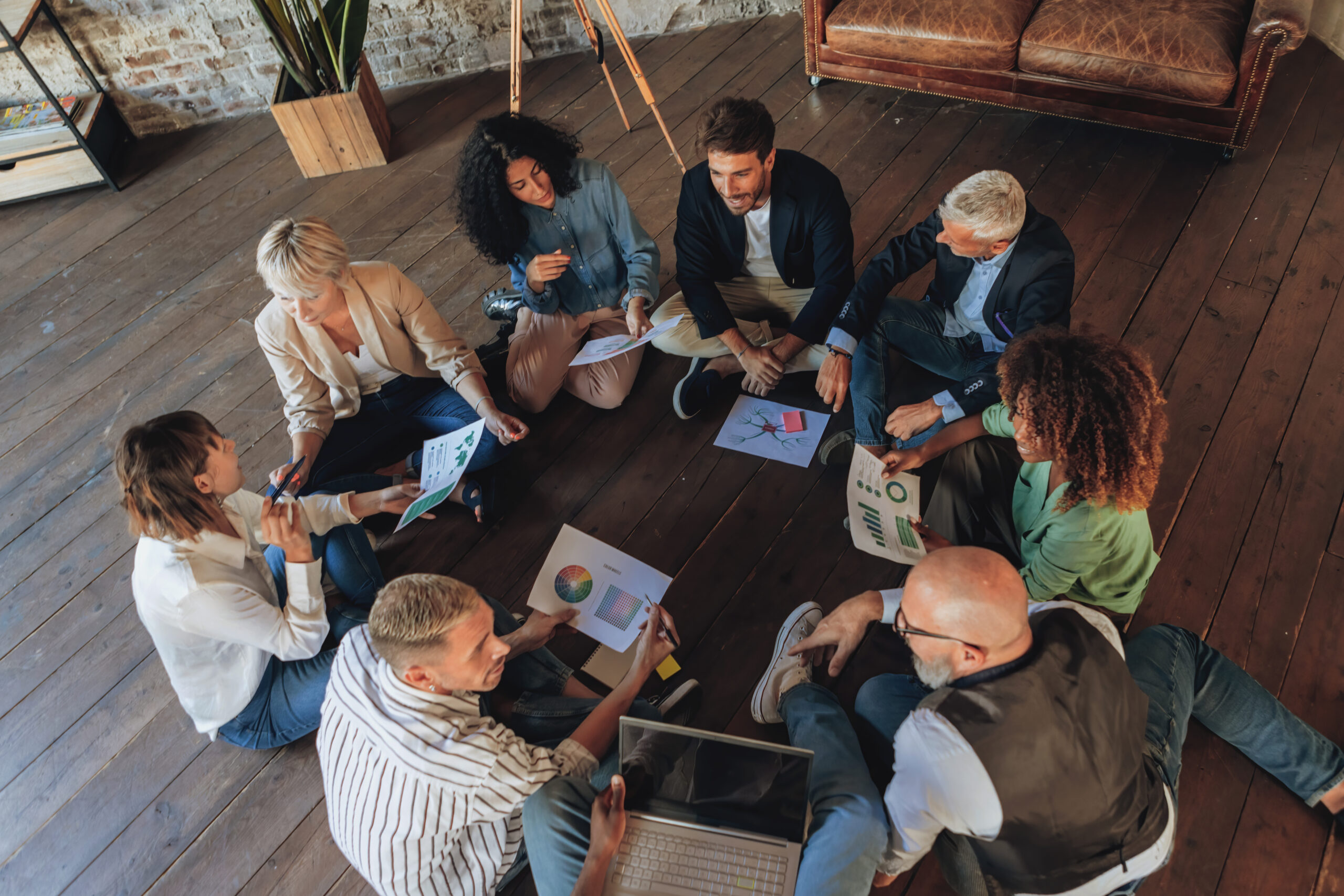 high angle of multiethnic creative business team brainstorming in modern office on a marketing project sitting on floor
