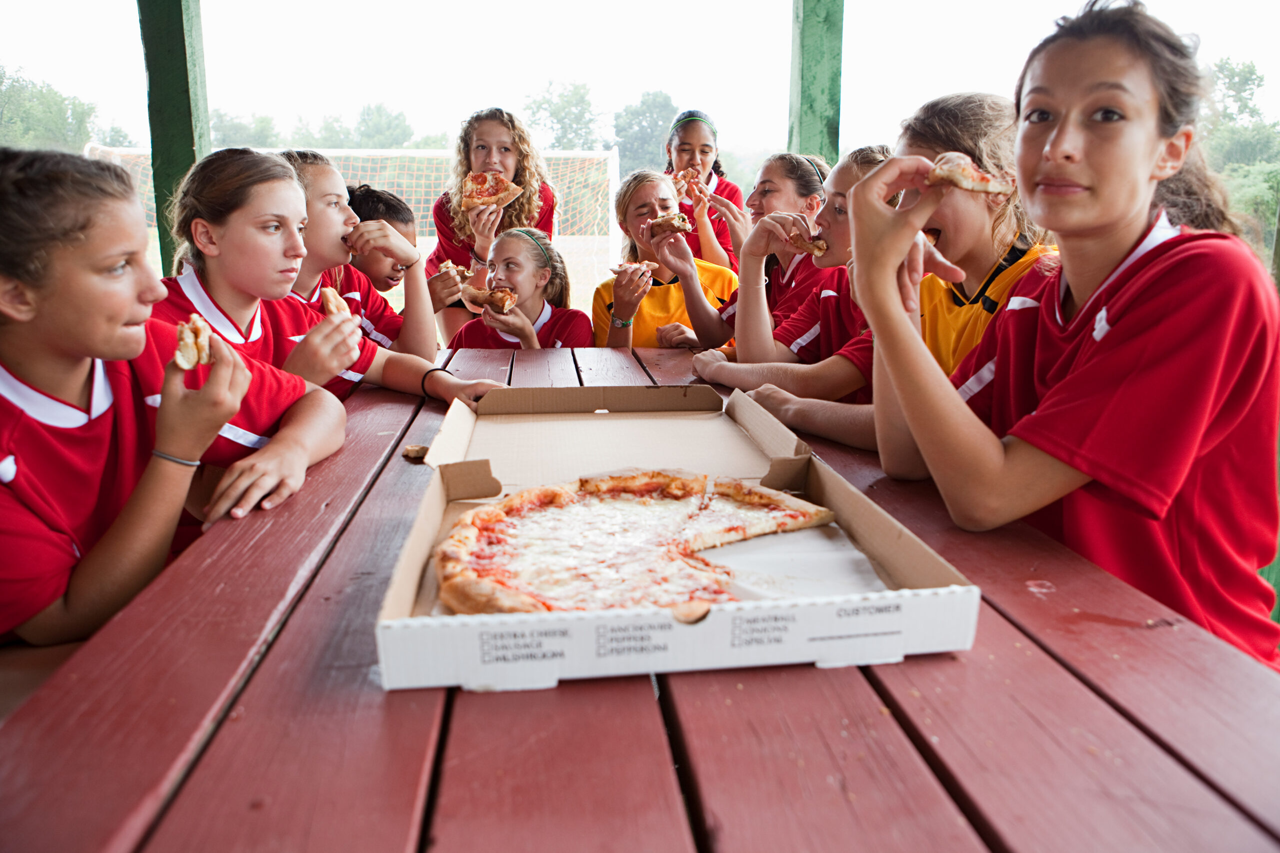 Female soccer team having pizza